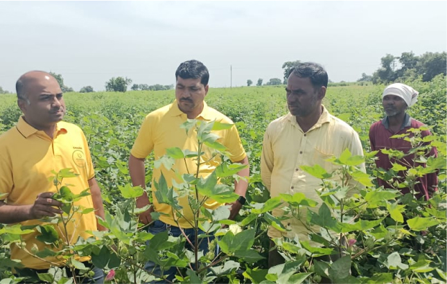 Tushar Malasane standing with some people and farmers in a field.