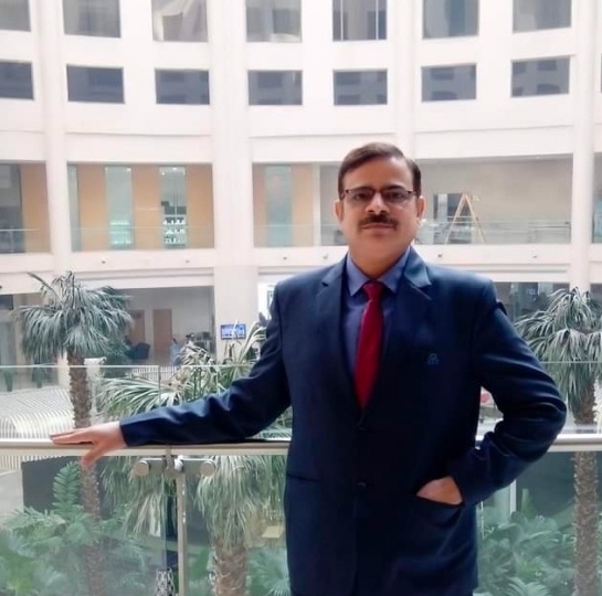 Subodh Kumar wearing a dark blue suit and standing in a balcony of an office building.