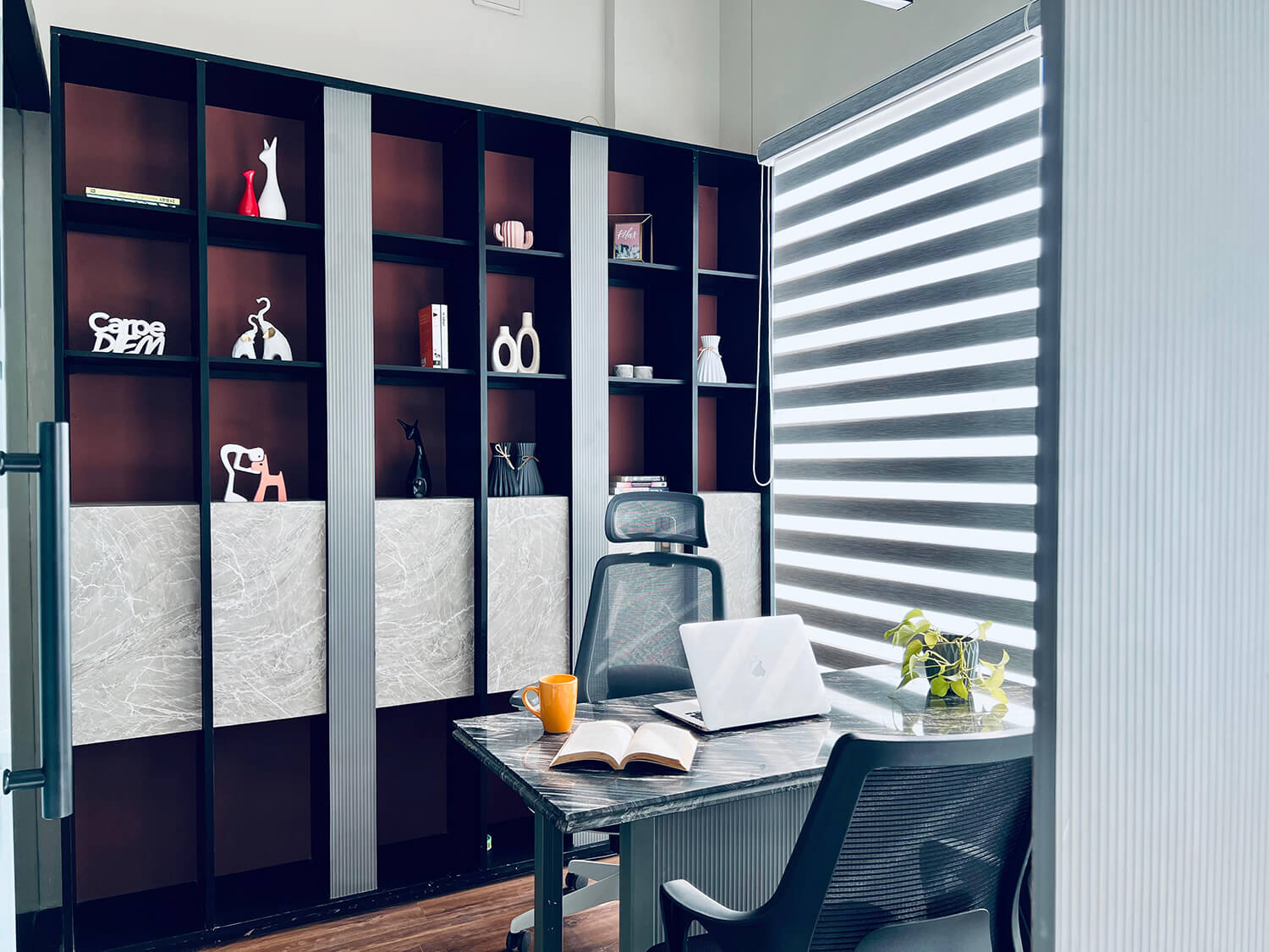 Interior view of a cabin that includes a chair, desk, laptop, book, and a wall laden with showpieces.