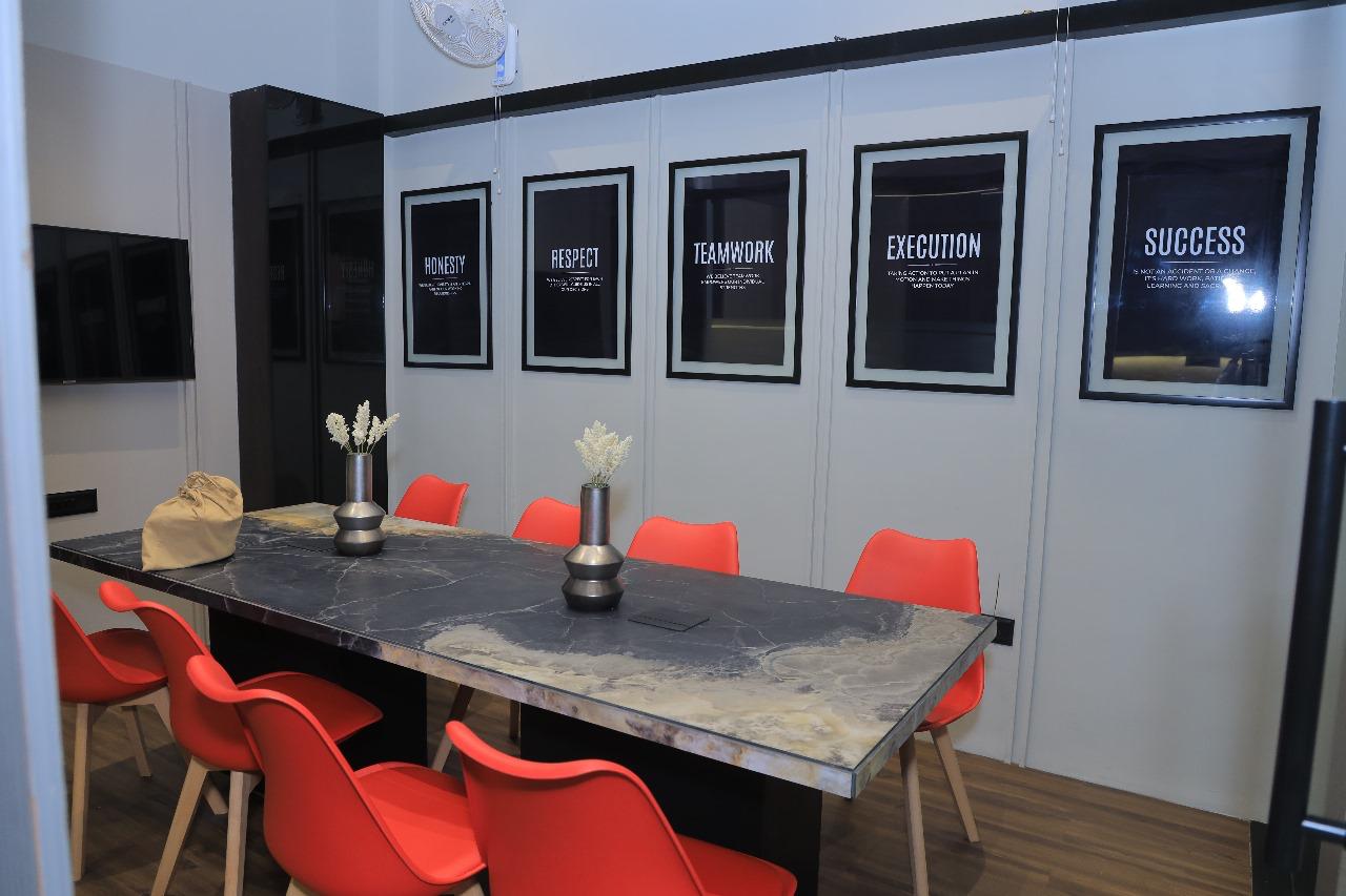 Conference room with rectangular table and four chairs. Posters on the wall say "Honesty," "Respect," "Teamwork," and "Execution."