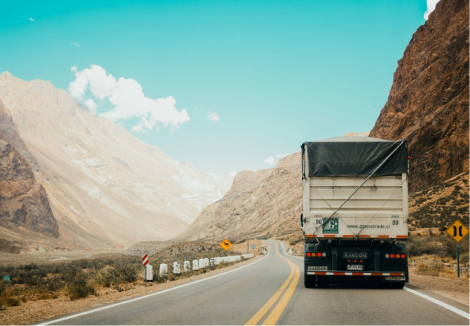 A truck carrying goods on a highway through a mountainous region.