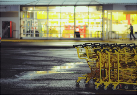 Trolleys placed one after another on a wet road, outside a shopping mart.